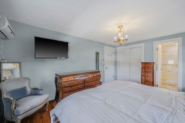 bedroom featuring ensuite bathroom, an AC wall unit, wood-type flooring, an inviting chandelier, and a closet