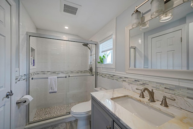 bathroom featuring a shower with door, vanity, tile walls, and toilet