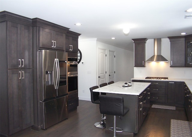 kitchen with stainless steel appliances, a kitchen island, dark brown cabinets, and wall chimney exhaust hood