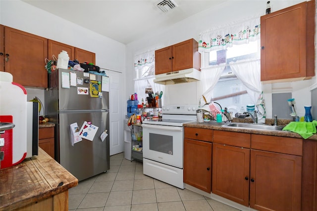 kitchen with stainless steel refrigerator, light tile patterned floors, sink, and electric range