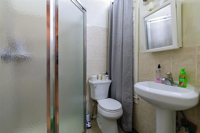 bathroom with toilet, a shower with shower door, and tile walls