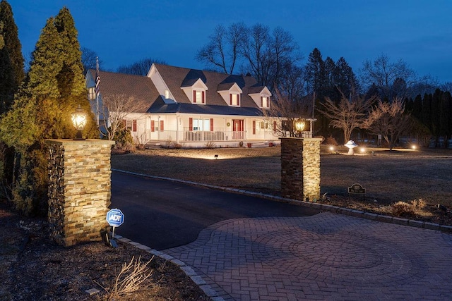 cape cod-style house with covered porch and curved driveway