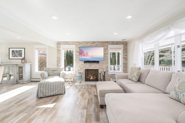 living area with ornamental molding, a baseboard radiator, a fireplace, and light wood-style flooring