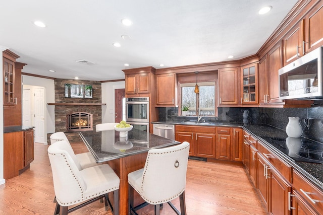 kitchen with glass insert cabinets, brown cabinets, a kitchen breakfast bar, a center island, and stainless steel appliances