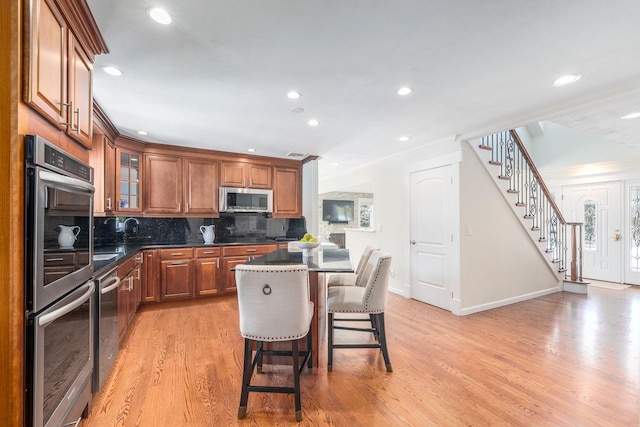 kitchen with a kitchen island, appliances with stainless steel finishes, tasteful backsplash, dark countertops, and glass insert cabinets