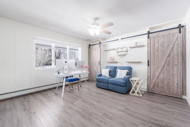 office featuring a barn door, visible vents, baseboard heating, and wood finished floors