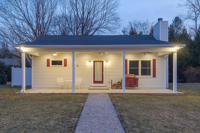 bungalow featuring a chimney, entry steps, a front yard, a patio area, and fence