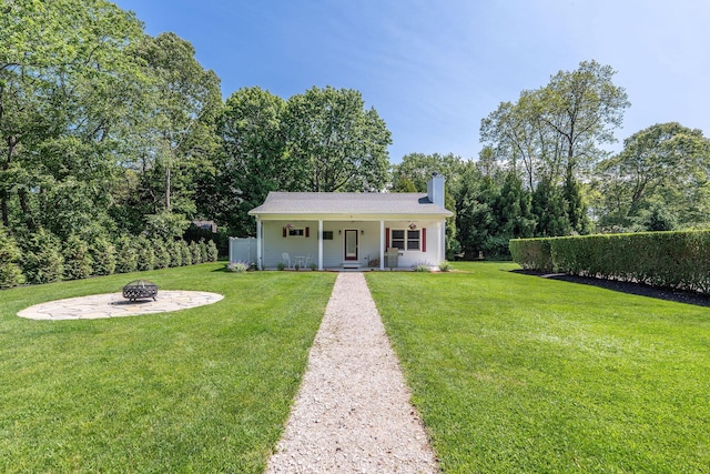 1125 Ole Jule Ln, Mattituck, NY 11952 - view of front facade featuring a fire pit, a chimney, a front lawn, a porch, and view of scattered trees