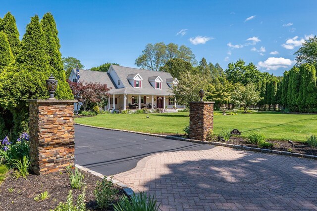 1125 Ole Jule Ln, Mattituck, NY 11952 - cape cod-style house featuring a front yard, covered porch, and a chimney