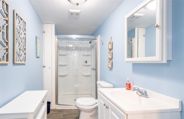 bathroom featuring wood-type flooring, toilet, vanity, and a shower with shower door