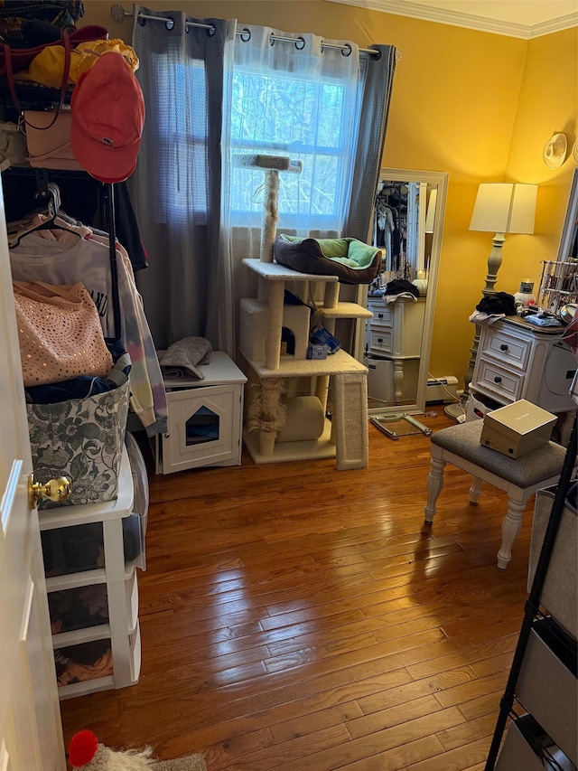 interior space with crown molding, a baseboard heating unit, and hardwood / wood-style flooring