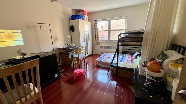 bedroom with radiator heating unit and dark hardwood / wood-style floors