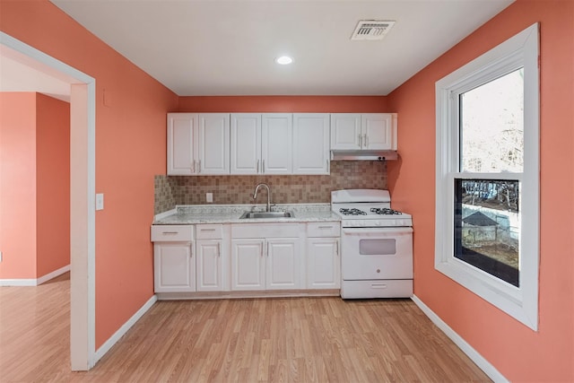 kitchen featuring sink, light hardwood / wood-style flooring, white cabinetry, tasteful backsplash, and white gas stove