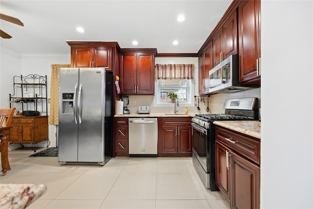 kitchen featuring sink, ceiling fan, stainless steel appliances, light stone counters, and ornamental molding