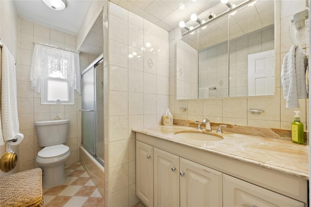 full bathroom featuring tile walls, vanity, bath / shower combo with glass door, and toilet