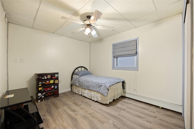 bedroom featuring a baseboard heating unit, a paneled ceiling, ceiling fan, and light hardwood / wood-style flooring