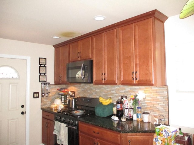 kitchen featuring dark stone countertops, decorative backsplash, and black gas stove