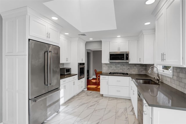 kitchen featuring white cabinetry, stainless steel appliances, sink, and backsplash