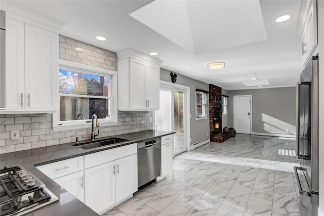 kitchen featuring sink, white cabinetry, a baseboard radiator, appliances with stainless steel finishes, and backsplash