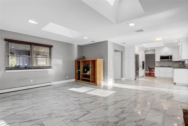 unfurnished living room featuring sink, baseboard heating, and a skylight