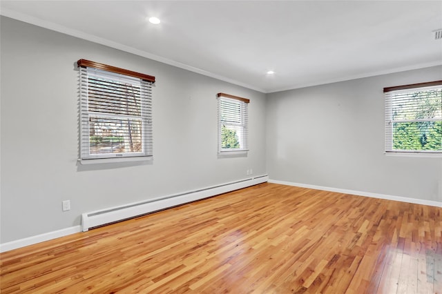 spare room featuring ornamental molding, baseboard heating, and light hardwood / wood-style flooring