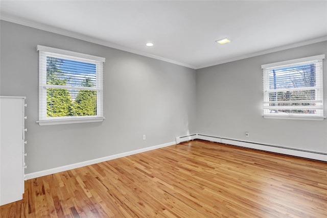 unfurnished room with ornamental molding, a baseboard heating unit, light hardwood / wood-style floors, and plenty of natural light