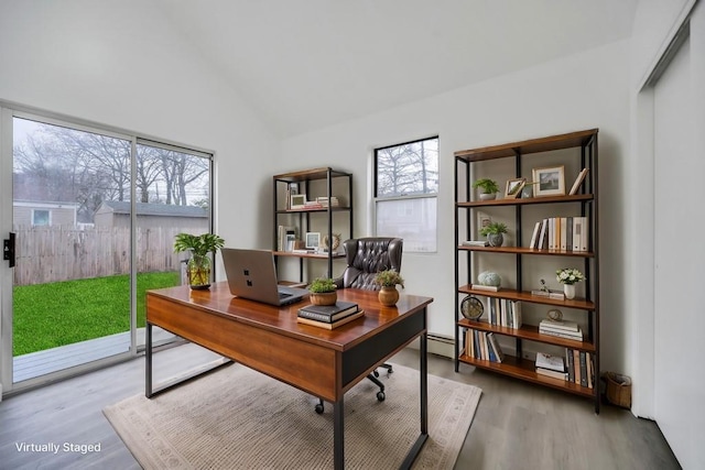 office featuring lofted ceiling, a baseboard heating unit, and wood-type flooring