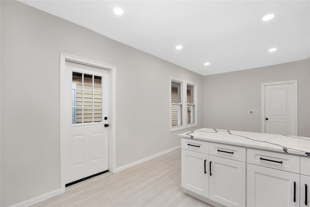 kitchen featuring light stone countertops, white cabinets, and light wood-type flooring