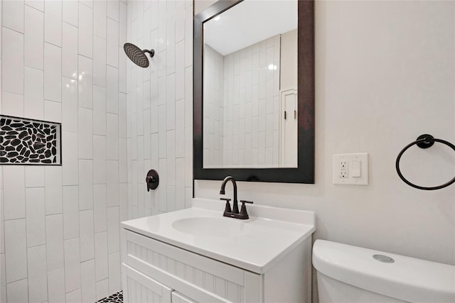 bathroom with vanity, toilet, and tiled shower