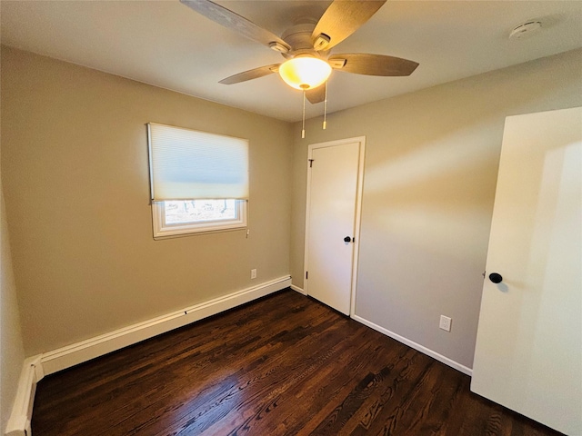 empty room featuring ceiling fan, dark hardwood / wood-style floors, and a baseboard heating unit