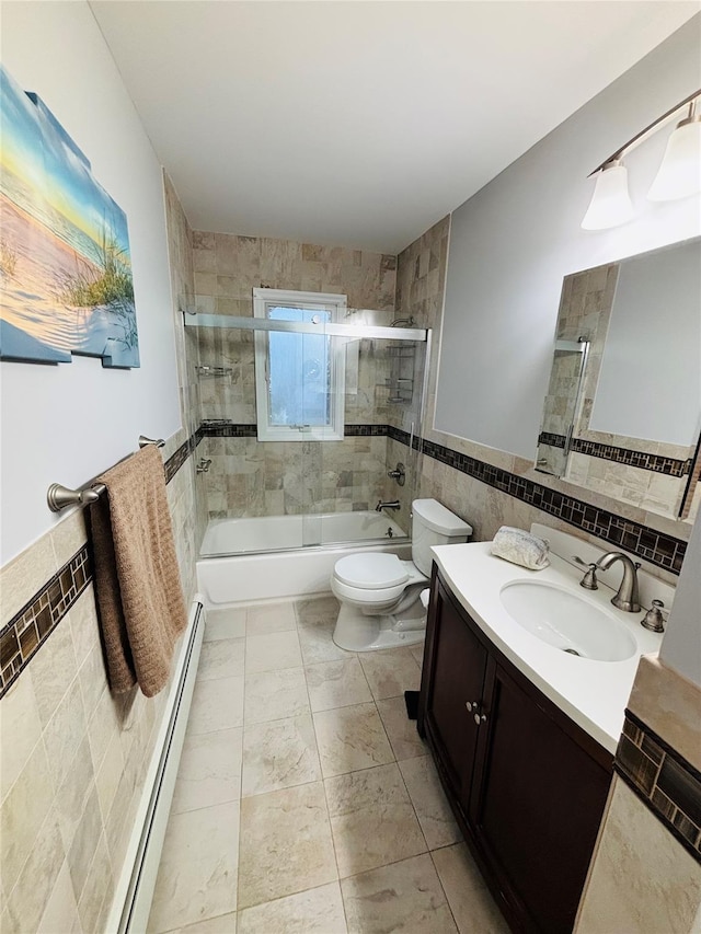 full bathroom featuring tile walls, shower / bath combination with glass door, vanity, baseboard heating, and toilet