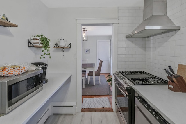 kitchen with stainless steel appliances, tasteful backsplash, wall chimney range hood, and light wood-type flooring