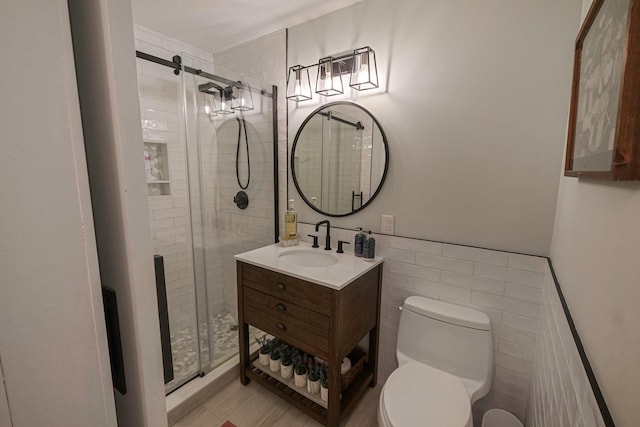 bathroom featuring vanity, toilet, a shower with shower door, and tile walls