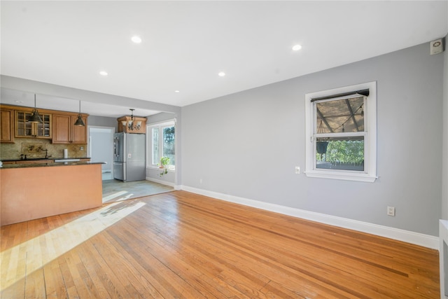 unfurnished living room with a chandelier and light hardwood / wood-style floors