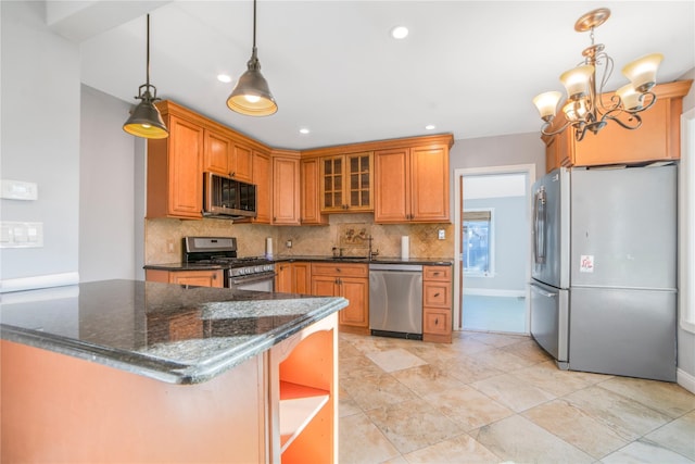 kitchen featuring sink, hanging light fixtures, dark stone counters, stainless steel appliances, and decorative backsplash