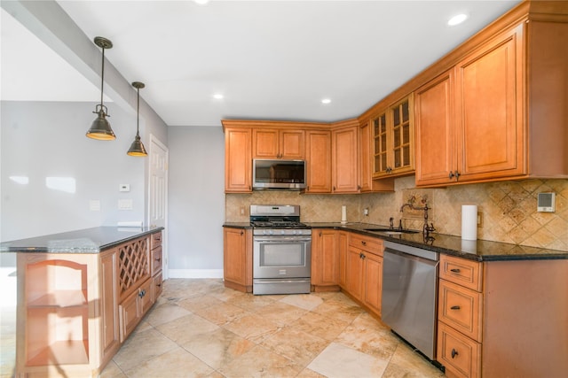 kitchen with appliances with stainless steel finishes, decorative light fixtures, tasteful backsplash, sink, and dark stone counters