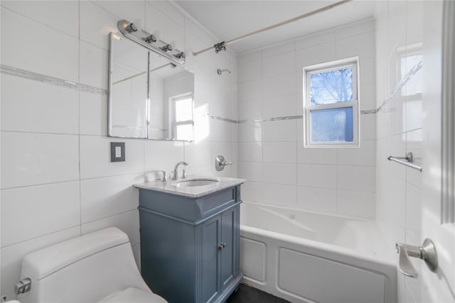 full bathroom with vanity, toilet, tiled shower / bath combo, and tile walls