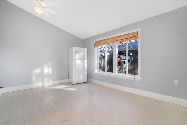 empty room with ceiling fan, vaulted ceiling, and light wood-type flooring