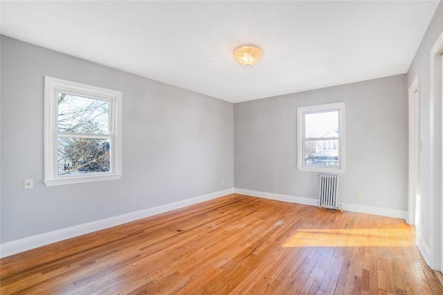 empty room with hardwood / wood-style floors and radiator heating unit