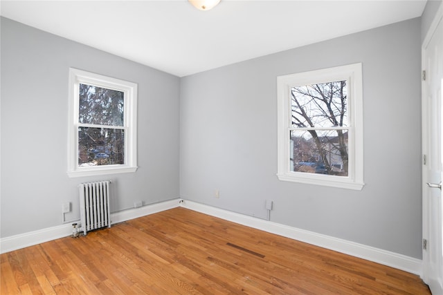 empty room with hardwood / wood-style floors and radiator heating unit