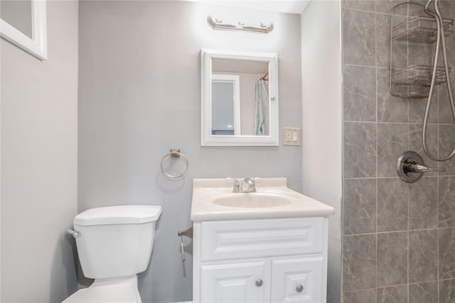 bathroom with vanity, a tile shower, and toilet