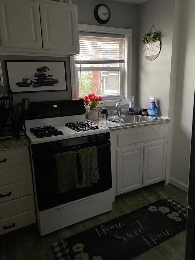 kitchen with hardwood / wood-style flooring, white cabinetry, sink, and gas range oven