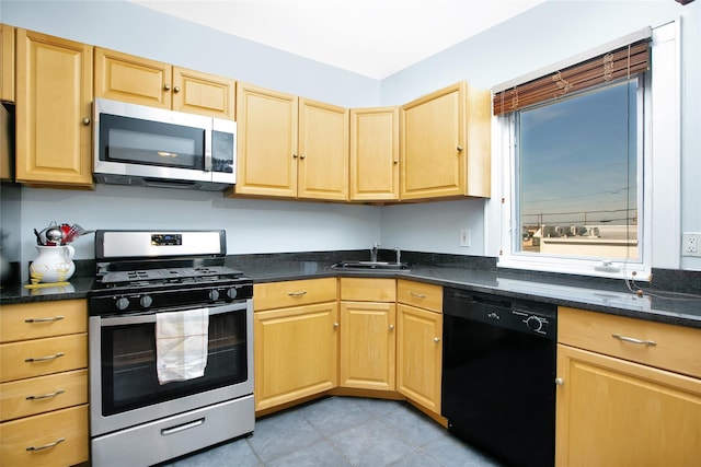 kitchen with appliances with stainless steel finishes, sink, light tile patterned floors, and light brown cabinetry