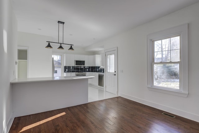 kitchen with white cabinetry, a healthy amount of sunlight, kitchen peninsula, and hanging light fixtures