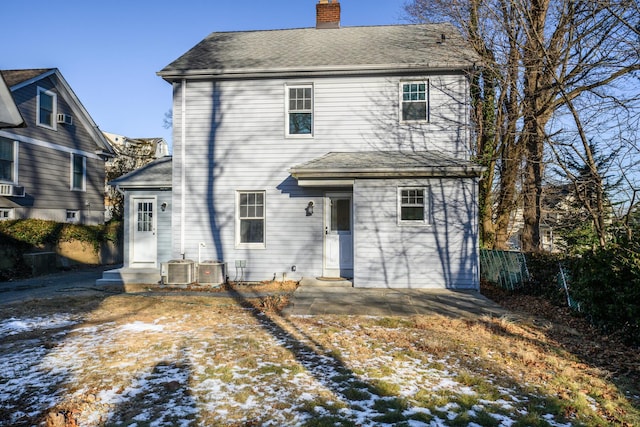 snow covered rear of property featuring central AC unit