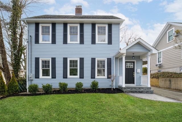 colonial house featuring a chimney and a front lawn