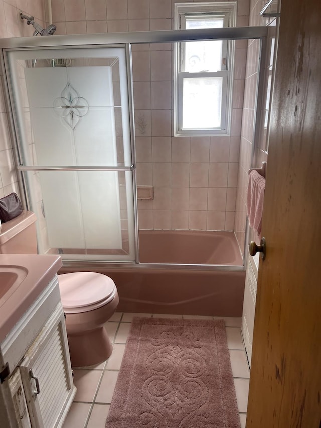 full bathroom featuring tile patterned flooring, vanity, combined bath / shower with glass door, and toilet