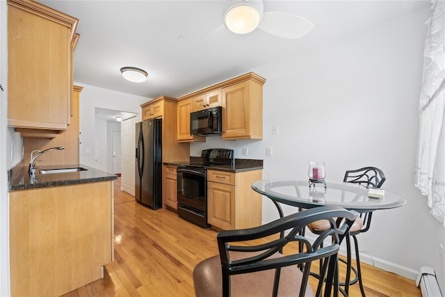 kitchen with sink, baseboard heating, black appliances, light brown cabinets, and light hardwood / wood-style flooring