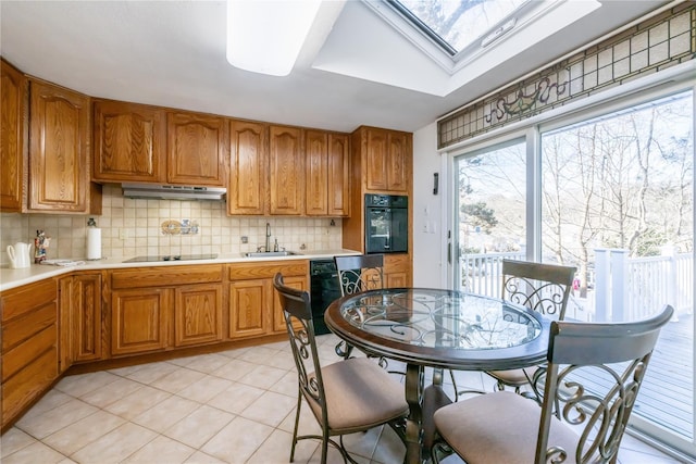 kitchen featuring sink, black appliances, a skylight, light tile patterned floors, and backsplash