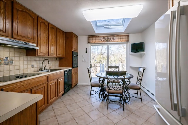 kitchen featuring a skylight, tasteful backsplash, sink, light tile patterned floors, and black appliances